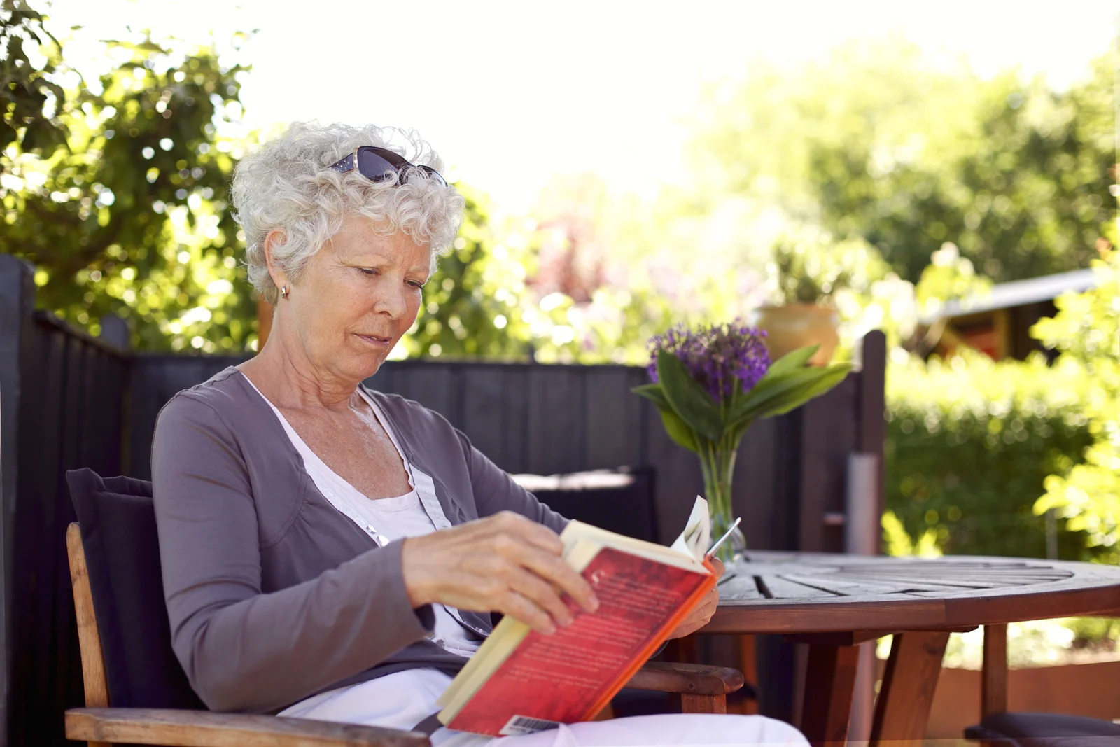 Senior Woman Reading on Patio on a Sunny Day